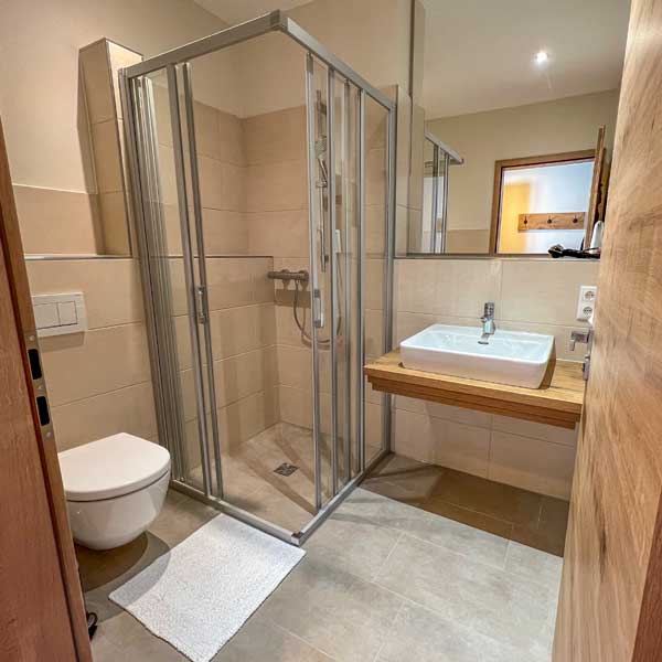 Modernes Bad am Zimmer mit Dusche, WC, Waschbecken und Fön